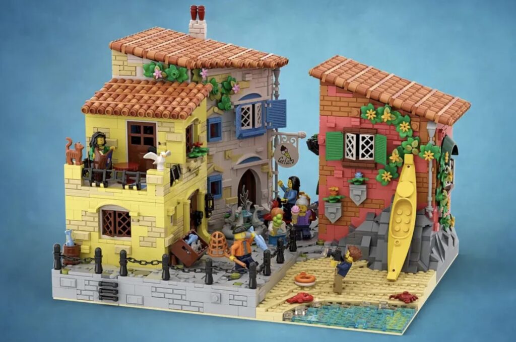 Image of LEGO Ideas The Italian Riviera, showing multiple colorful buildings, a section of beach and ocean, and numerous minifigures